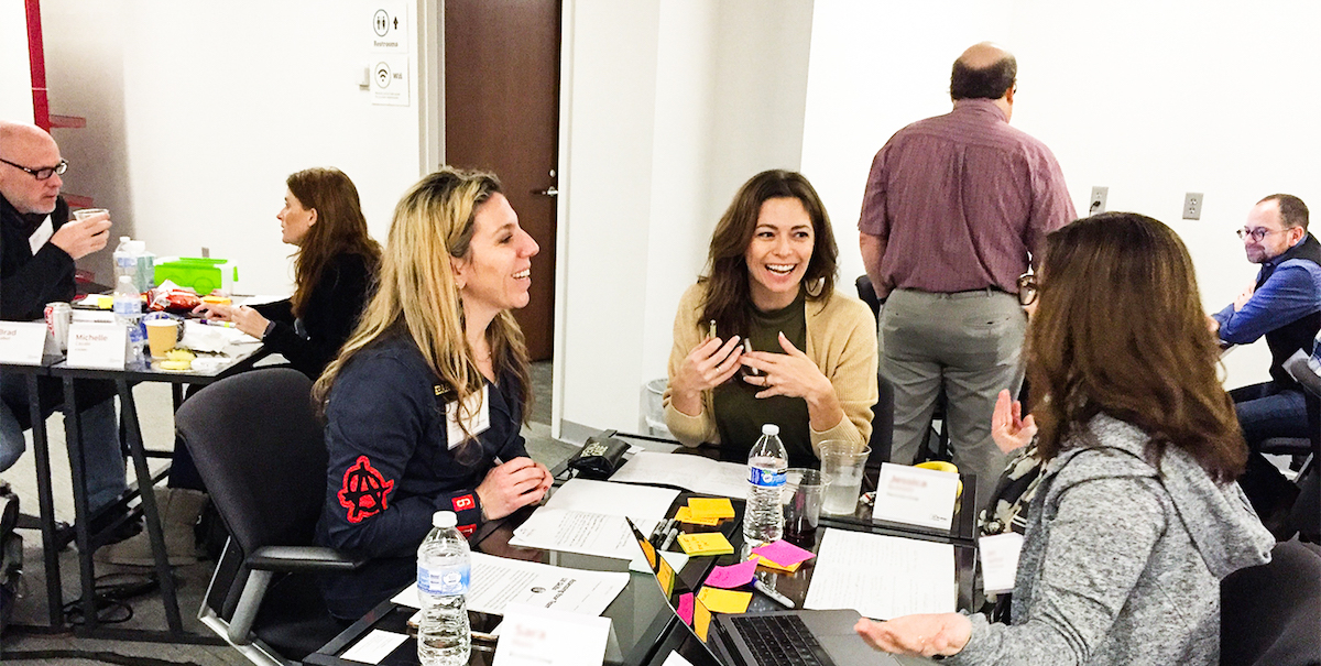 Photo of a group of three team members laughing and creating their UX strategy game plan.