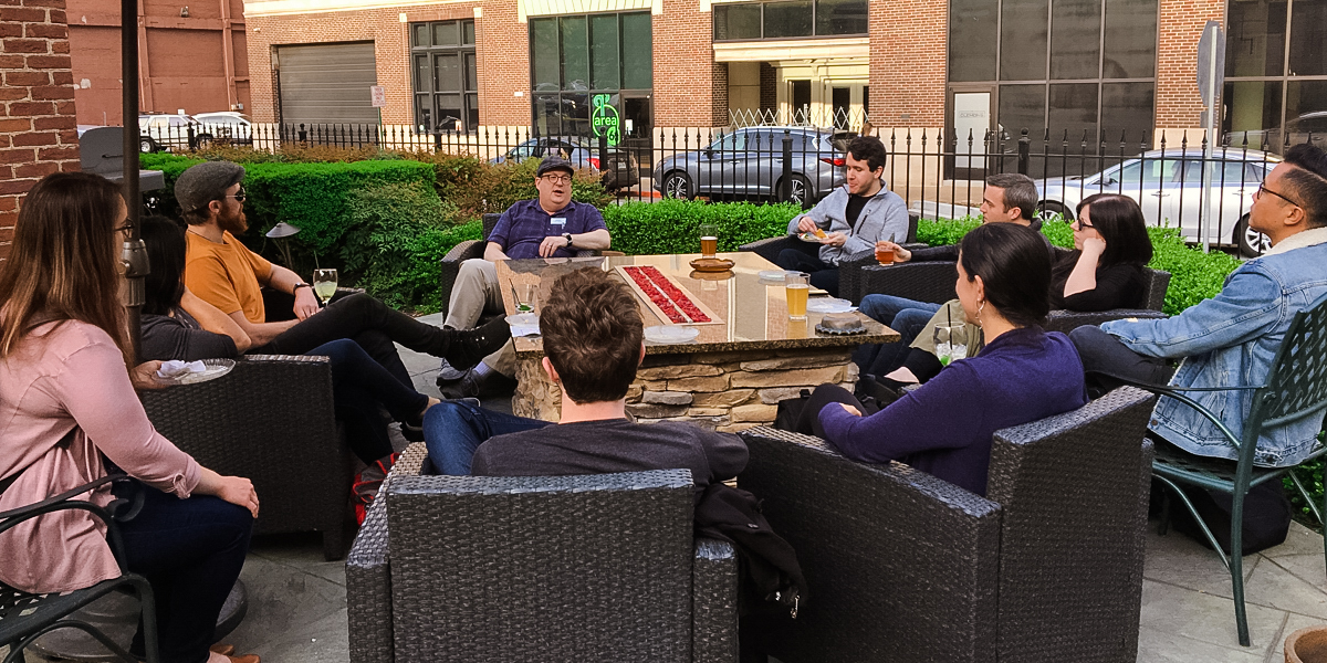 Photo of Jared on an outdoor patio surrounded by workshop attendees during the workshop Happy Hour.
